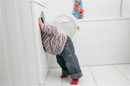 standing on tip toes - Baby boy looking into a washing machine Stock Photo - Premium Royalty-Free, Code: 628-00920322