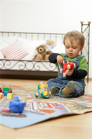 Baby boy with a toy sitting on a play carpet Stock Photo - Premium Royalty-Free, Code: 628-00920335