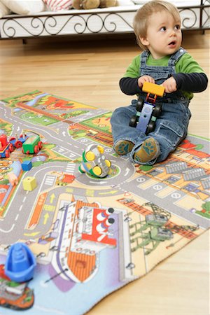 Baby boy with toy sitting on a play carpet Stock Photo - Premium Royalty-Free, Code: 628-00920360