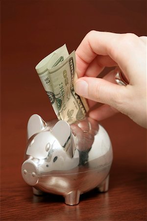 piggy bank hand - Silver piggybank with a bill sticking in it's back, close-up Stock Photo - Premium Royalty-Free, Code: 628-00920474