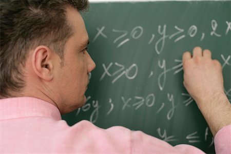 Teacher writing an arithmetic problem on blackboard Stock Photo - Premium Royalty-Free, Code: 628-00920635