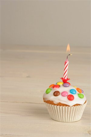 Birthday muffin with icing, sprinkles and candle Stock Photo - Premium Royalty-Free, Code: 628-00920745