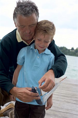 Gray-haired man with a boy in front of him is repairing a boat, selective focus Stock Photo - Premium Royalty-Free, Code: 628-01278158