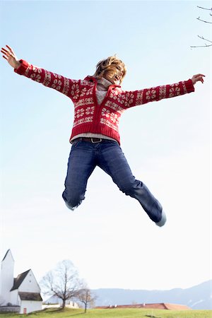 Young woman jumping into the air in front of a small town Stock Photo - Premium Royalty-Free, Code: 628-01278153