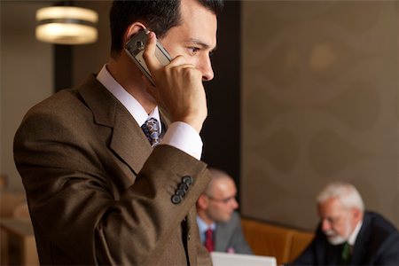 simsearch:628-01279499,k - Businessman phoning with a mobile phone, two businessmen in background Fotografie stock - Premium Royalty-Free, Codice: 628-01278189