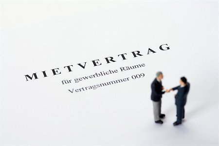 Businessmen figurines standing on a rental agreement shaking hands Stock Photo - Premium Royalty-Free, Code: 628-01278272
