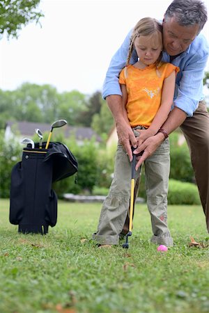 Senior adult man is teaching a girl how to play golf, selective focus Stock Photo - Premium Royalty-Free, Code: 628-01278304