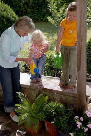 Little girls are watering flowers with their grandmother, selective focus Stock Photo - Premium Royalty-Free, Code: 628-01278350