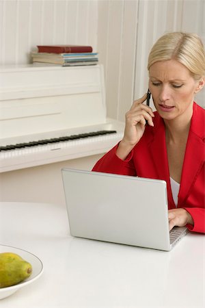 Blond girl is sitting next to her mother behind a laptop, close-up Stock Photo - Premium Royalty-Free, Code: 628-01278547