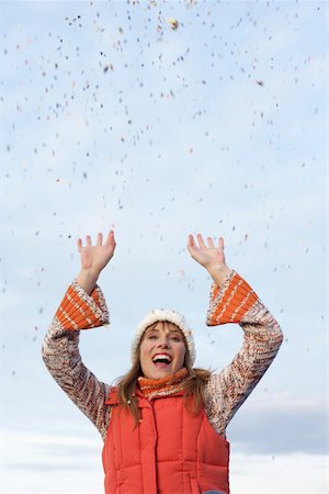 Young woman with scarf and cardigan under the sky while playing with confetti, close-up Stock Photo - Premium Royalty-Free, Code: 628-01278692