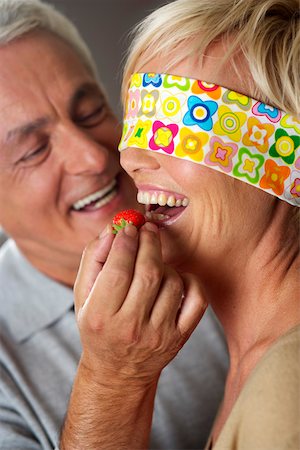 simsearch:628-01279142,k - Gray-haired man letting a woman, who's eyes are covered, taste a strawberry, close-up Foto de stock - Royalty Free Premium, Número: 628-01278722