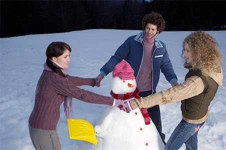 Three young people making a snowman Stock Photo - Premium Royalty-Free, Code: 628-01278798