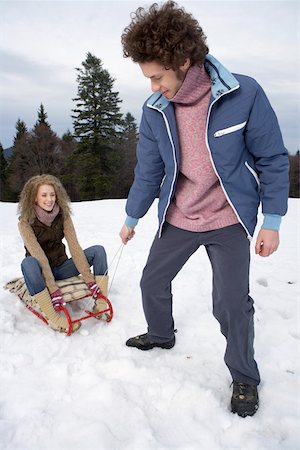 simsearch:628-01495418,k - Young man pulling a sled with a blonde woman sitting on it Foto de stock - Sin royalties Premium, Código: 628-01278847