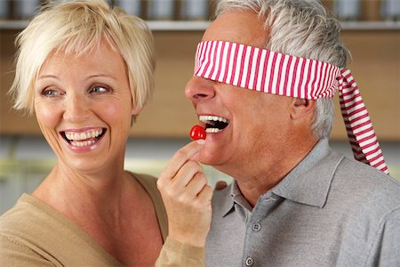 simsearch:628-01279142,k - Blonde woman letting a man, who's eyes are covered, taste a red pepper, close-up Foto de stock - Royalty Free Premium, Número: 628-01279047