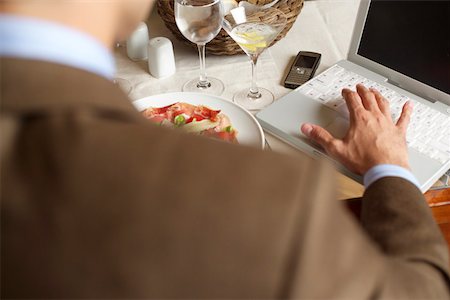 Businessman using a laptop while he eating Stock Photo - Premium Royalty-Free, Code: 628-01279062