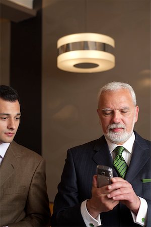 simsearch:628-01278542,k - Two businessmen side by side, mature man holding a mobile phone Stock Photo - Premium Royalty-Free, Code: 628-01279070