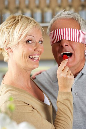 simsearch:628-01279142,k - Blonde woman letting a man, who's eyes are covered, taste a red pepper, close-up Foto de stock - Royalty Free Premium, Número: 628-01279134