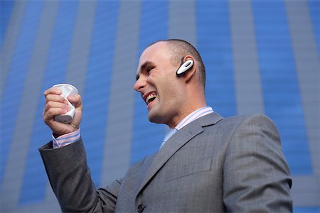Businessman with headset crushing a beaker Stock Photo - Premium Royalty-Free, Code: 628-01279188