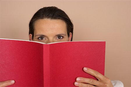 Woman looking over a red book Stock Photo - Premium Royalty-Free, Code: 628-01279267