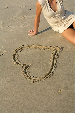 Woman sitting next to a heart drawn into the sand , high angle view Foto de stock - Sin royalties Premium, Código: 628-01279285