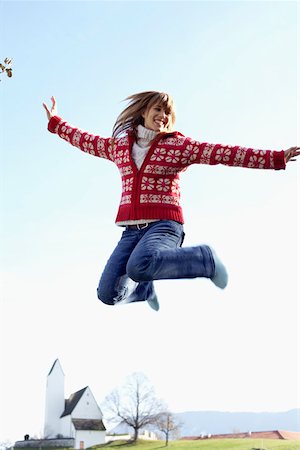 Young woman jumping into the air in front of a small town Stock Photo - Premium Royalty-Free, Code: 628-01279341