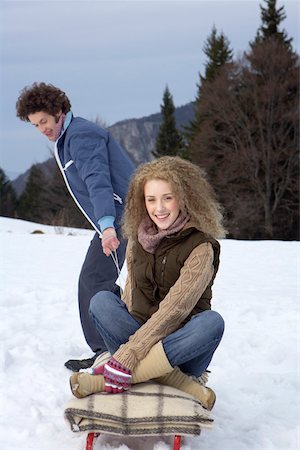 simsearch:628-01495418,k - Young man pulling a sled with a blonde woman sitting on it Foto de stock - Sin royalties Premium, Código: 628-01279357