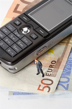 Businessman figurine next to mobile phone on a stack of Euro banknotes Stock Photo - Premium Royalty-Free, Code: 628-01279371