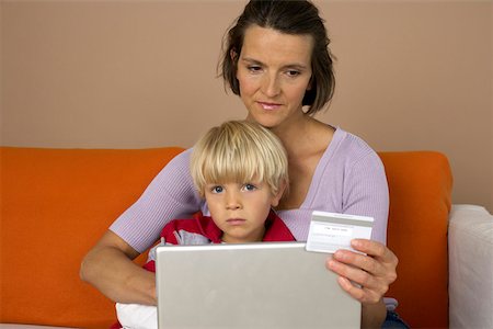 Mother and son (4-5 Years) using a laptop, mother holding credit card Stock Photo - Premium Royalty-Free, Code: 628-01279384