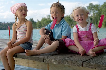 Three children each eating an ice lolly at a lake , close-up Foto de stock - Sin royalties Premium, Código: 628-01279424