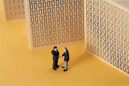 Two businessmen figurines shaking hands in front of models of high- rise buildings Stock Photo - Premium Royalty-Free, Code: 628-01279458