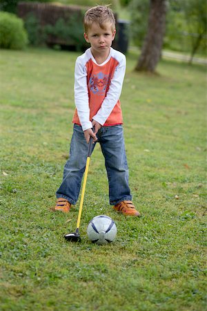 Little boy is standing on a meadow with a golf club in his hand, high angle view Stock Photo - Premium Royalty-Free, Code: 628-01279489