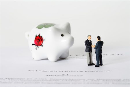 partnership symbol - Businessmen figurines and piggy bank on an agreement Stock Photo - Premium Royalty-Free, Code: 628-01279647