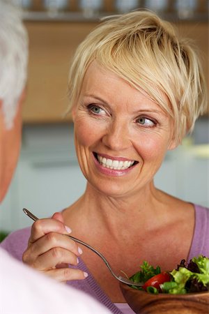 simsearch:628-01279142,k - Blond woman with a salad smiling at a man, selective focus, close- up Foto de stock - Royalty Free Premium, Número: 628-01279682