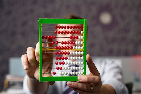 Businessman calculating with an abacus Stock Photo - Premium Royalty-Free, Code: 628-01279738