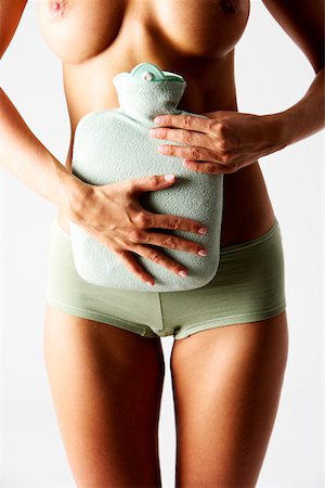 Skinny young woman holding a hot- water bottle against her belly (part of) Stock Photo - Premium Royalty-Free, Code: 628-01279754