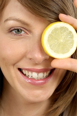 Mid adult woman holding a slice of lemon Stock Photo - Premium Royalty-Free, Code: 628-01494829