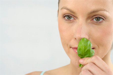 Mid adult woman smelling a basil leaf Stock Photo - Premium Royalty-Free, Code: 628-01494836