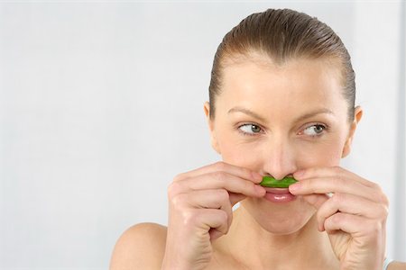 Mid adult woman smelling a basil leaf Stock Photo - Premium Royalty-Free, Code: 628-01494844