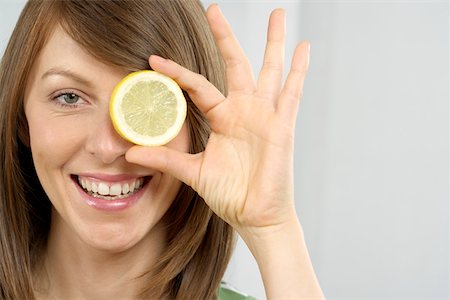 fruit eyes not children - Mid adult woman holding a slice of lemon Stock Photo - Premium Royalty-Free, Code: 628-01494857