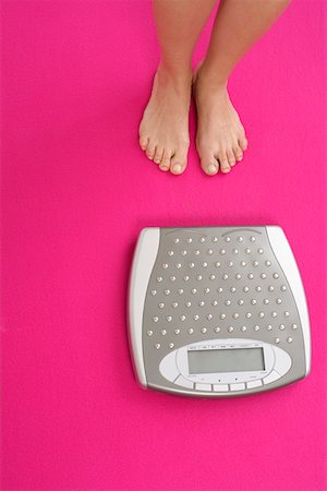 Woman feet and pink weight scale isolated on white background