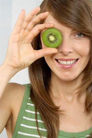 fruit eyes not children - Mid adult woman holding a slice of kiwi fruit Stock Photo - Premium Royalty-Free, Code: 628-01494866