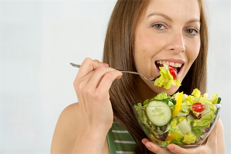 salad greens on white background - Mid adult woman eating salad Stock Photo - Premium Royalty-Free, Code: 628-01494875