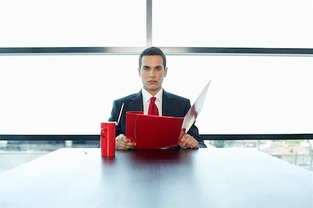 Businessman sitting at table, holding documents Stock Photo - Premium Royalty-Free, Code: 628-01495129