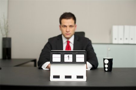 Businessman sitting at a table, calendar in foreground Stock Photo - Premium Royalty-Free, Code: 628-01495150