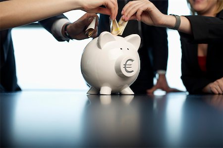 piggy bank hand - Businesspeople putting banknotes into a piggybank Stock Photo - Premium Royalty-Free, Code: 628-01495163