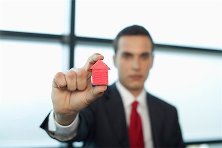 Businessman holding a model house between fingers Stock Photo - Premium Royalty-Free, Code: 628-01495170