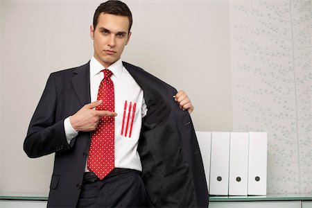 Businessman pointing at three pens in front pocket, portrait Stock Photo - Premium Royalty-Free, Code: 628-01495185