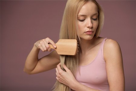 straight hair brushing - Young blonde woman brushing her hair, close-up Foto de stock - Sin royalties Premium, Código: 628-01495204