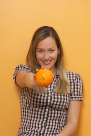 simsearch:628-01586779,k - A woman is holding an orange in her hand Stock Photo - Premium Royalty-Free, Code: 628-01586761