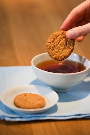 Hand putting some cakes into a tea Stock Photo - Premium Royalty-Free, Code: 628-01638940
